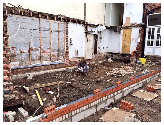 Lady builder sitting on building site designing a kitchen