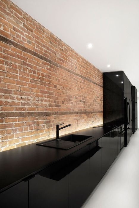 Bare brick wall in minimalist black kitchen